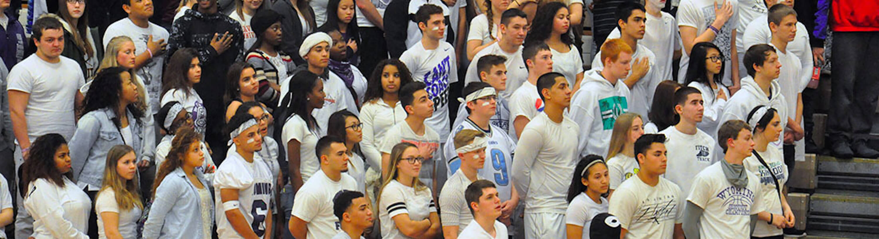 Photo of students listening to national anthem at basketball game
