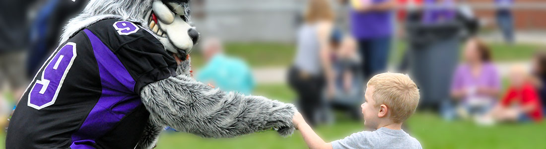 Photo of school mascot giving a young child a high five.